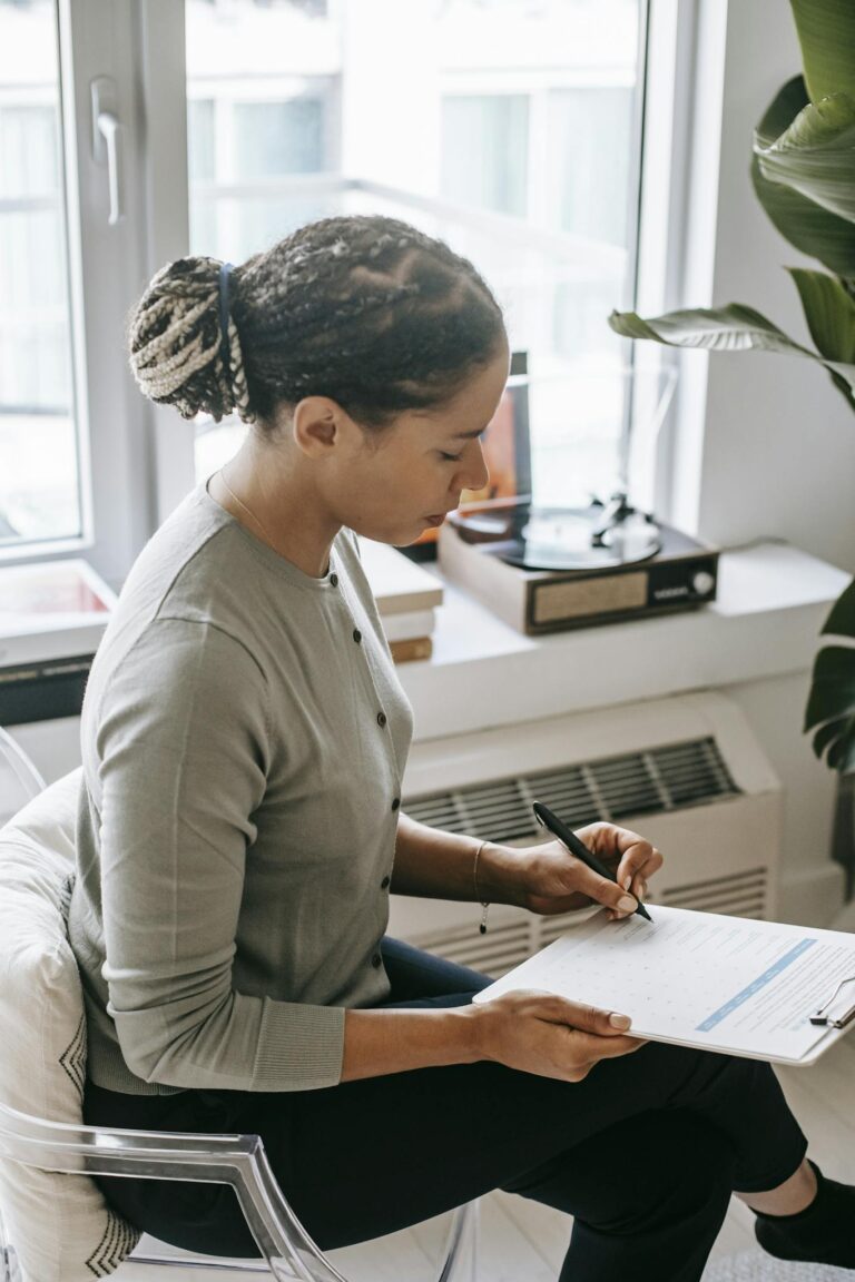 Focused ethnic woman writing on clipboard